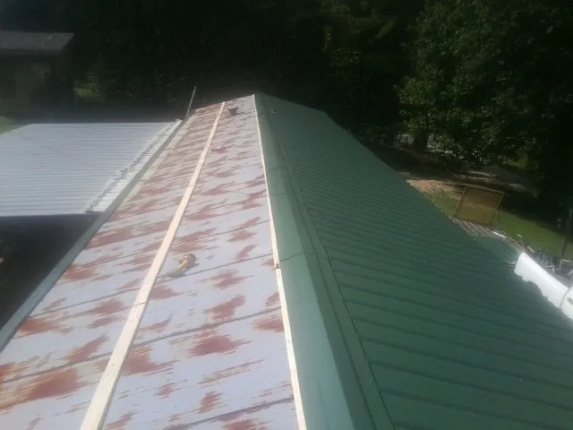 Old rusted panels beside newly installed green metal roofing — Wind Damage Roof Repair by Roofing Brothers in Isleton