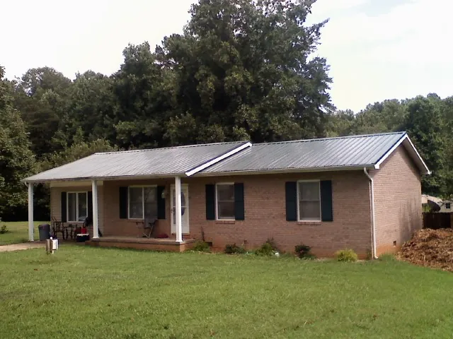 Gray metal roof on a brick ranch house with a side carport in Isleton