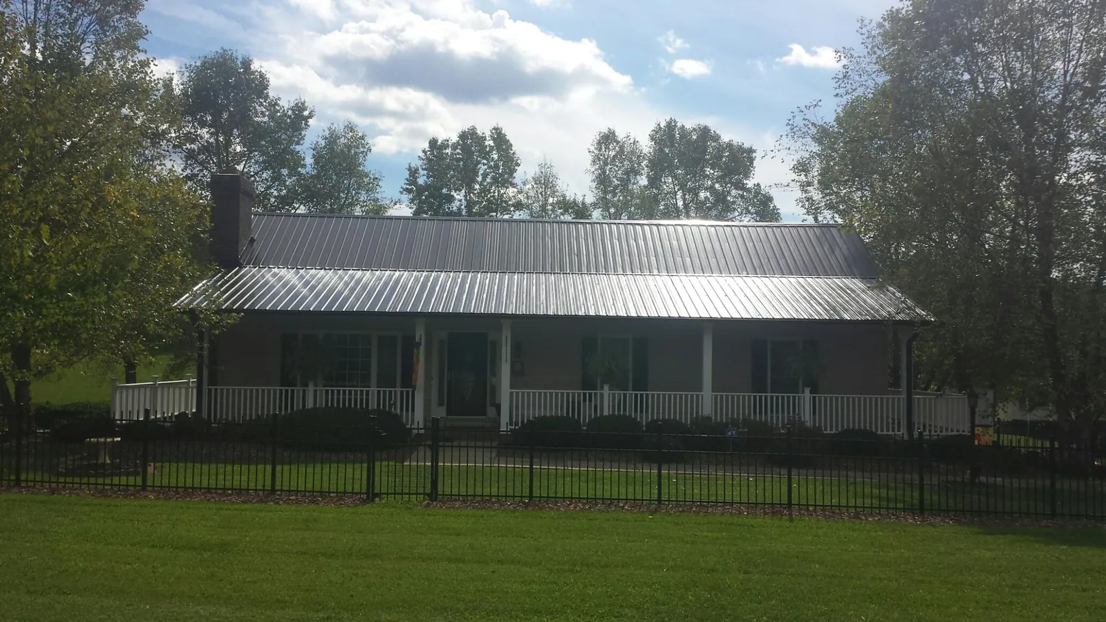 Gray metal roof on a brick ranch with a full width front porch — Gutter Guard Installation work by our crew in Isleton