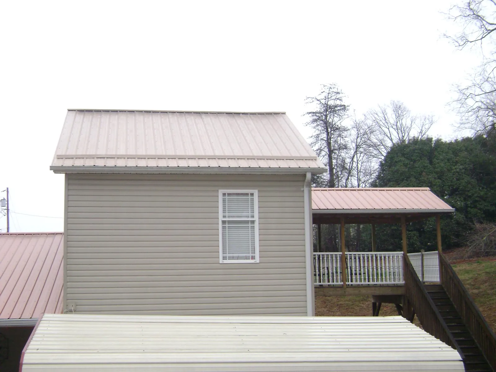 Tan metal roofs on a two story addition and attached porch, from a Roof Replacement job in Isleton