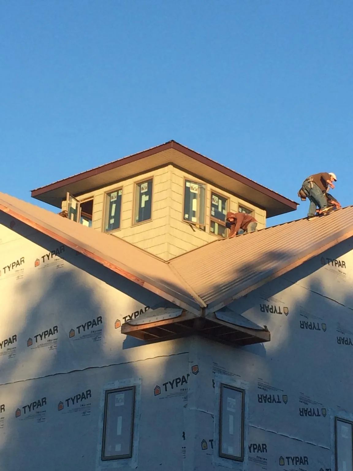 Roofers working around a rooftop cupola on a new metal roof at sunset — Roof Waterproofing in Isleton by Roofing Brothers